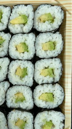 there are many pieces of sushi in the box with avocado on top