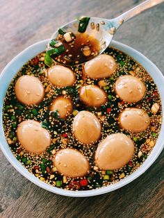 a bowl filled with food on top of a wooden table next to a metal spoon