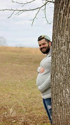 a man standing next to a tree with his belly wrapped around the tree's trunk