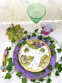 there is a purple plate with green leaves on it and two glasses next to it