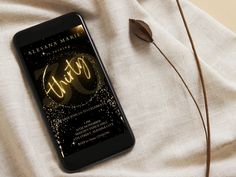 a cell phone sitting on top of a bed next to a plant with the words happy written on it