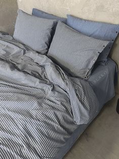 an unmade bed with blue and white striped comforter on it's side