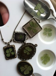 four leaf clover necklaces are sitting on a tray next to two spoons and plates