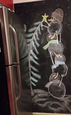 a chalk drawing on the side of a refrigerator in a kitchen with pine cones and snowmen