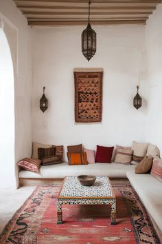 a living room filled with lots of furniture and pillows on top of a red rug