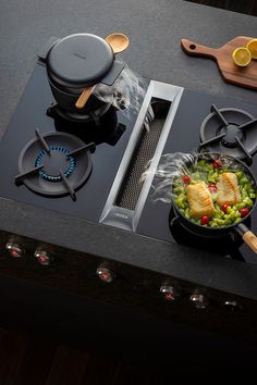 a stove top with two burners and some food cooking on the burner area