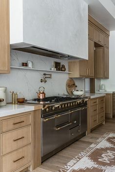 a kitchen with wooden cabinets and white counter tops, an oven hood over the stove