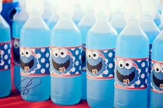 blue water bottles are lined up on a red tablecloth with cartoon characters painted on them