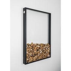 a black frame holds a pile of firewood in front of a wall mounted mirror