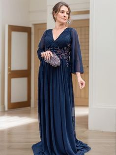 a woman in a long blue dress is standing on the floor with her handbag