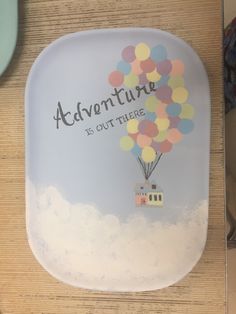 there is a plate with a house on it that says adventure is out there and balloons are floating in the sky