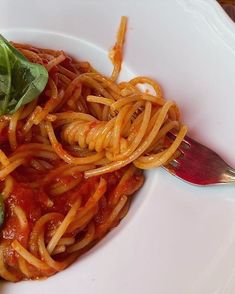 a white plate topped with pasta and spinach