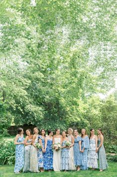 a group of women in dresses standing next to each other on a lush green field