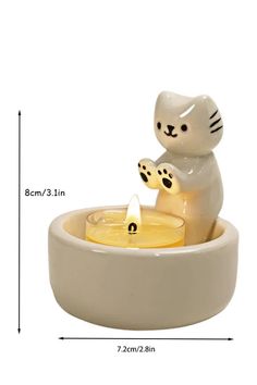 a cat figurine sitting on top of a bowl filled with water and candles