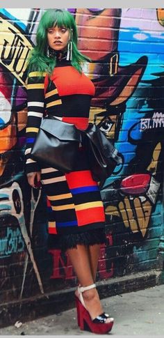 a woman standing in front of a graffiti wall with her hand on her hip bag