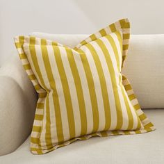 a yellow and white striped pillow sitting on top of a couch