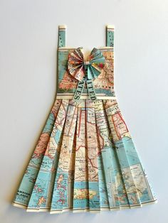 a dress made out of maps with a bow on the front and back, sitting on a white surface