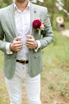 a man in a green jacket and white pants is holding his hands on his chest