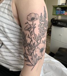 a woman's arm with flowers on it and a striped shirt in the background