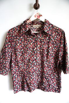 Blouse details: * Floral blouse * Button closure on front * Short sleeves * Condition: Perfect vintage condition Measurements: Length: 22 1/2" / 57 cm Armpit to armpit: 21" / 53 cm Shoulder to shoulder: 16 1/2" / 42 cm Sleeve: 14" / 35 cm Label size: looks like medium, please check measurements Feel free to message me with any questions Floral Print Short Sleeve Work Shirt, Short Sleeve Floral Print Shirt For Work, Workwear Floral Print Short Sleeve Shirt, Fall Patterned Short Sleeve Blouse, Floral Print Cotton Blouse With Collar, Cotton Blouse With Floral Print And Collar, Summer Floral Print Shirt With 3/4 Sleeves, Cotton Ditsy Floral Print Short Sleeve Blouse, Daywear Floral Print Button-up Shirt