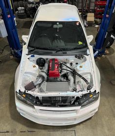 the engine compartment of a white car in a garage