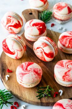 red and white macaroons with icing on a wooden board next to other macaroons