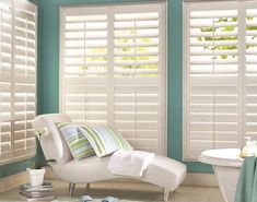 a bathroom with blue walls and white shutters on the windows, including a bathtub