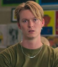 a young man with blonde hair wearing a green shirt