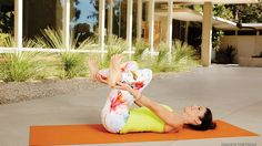 a woman is doing yoga outside on an orange mat