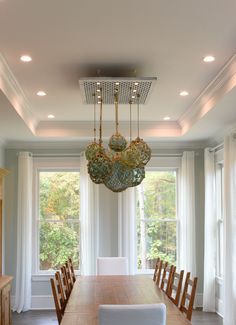 a dining room table with chairs and a chandelier hanging from it's ceiling