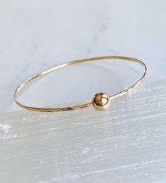 This cool single bangle was hand forged from 14kt gold fill wire and hammered with a dappled texture to catch the light.  It looks great stacked with other bangles you already  have but also fantastic on its own for a minimalist look. It features a 8mm 14kt gold fill ball that slides freely around the bangle. The diameter of the bangle is 2 1/2”. Custom sizing available upon request Hammered Yellow Gold Bangle, Hammered Yellow Gold Bangle Bracelet, Adjustable Hammered Yellow Gold Bracelet, Hammered Yellow Gold Bangle For Everyday, Minimalist Hammered Bracelet Bangle, Minimalist Hammered Bangle Bracelet, Hammered Minimalist Bangle, Everyday Hammered Yellow Gold Bangle, Adjustable Hammered Gold Bangle