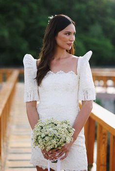 a woman in a short white dress holding a bouquet of baby's breath flowers