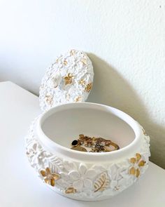 two white bowls with gold designs on them sitting on a table next to each other