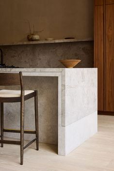 a kitchen with a counter, stools and a bowl on the stove top in front of it