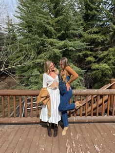 two women standing on a deck with trees in the background