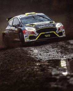 a rally car driving through the mud on a wet road