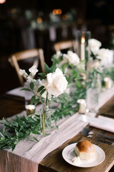 the table is set with white roses and greenery for an elegant dinnereonal