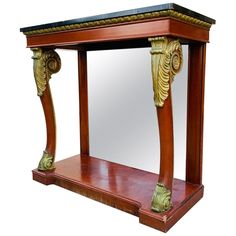 an ornate wooden table with mirror on it's side and gold leaf decoration around the edge