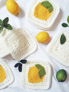 crocheted lemons and limes are displayed on a white surface with green leaves