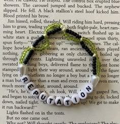 a bracelet with words written in white and green beads on top of an open book