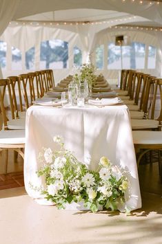 the table is set up with flowers and place settings for guests to sit down at