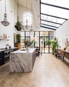 an open kitchen and dining room with wood flooring, marble counter tops and black appliances