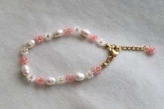 🌸 Dainty cherry blossom-inspired bracelet made with pink, white, and gold glass beads and freshwater pearl beads. 🐇 From the lobster claw to the chain extender, this bracelet is 7.5 inches in length. All bracelets will come with an extension chain. Hardware is gold-plated stainless steel. I can also adjust the length if you need it shorter or longer, just message me!   ☁️ All things are handmade carefully, but excess glue and string might be visible up close. To preserve this bracelet and all Daisy Bead Bracelet, Cherry Blossom Bracelet, Flower Bead Bracelet, Blossom Bracelet, Beads Ideas, Bracelet Pearl, Sakura Flower, Bracelet Dainty, Chain Extenders