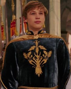 the young man is dressed in an elaborate black and gold outfit with golden trims