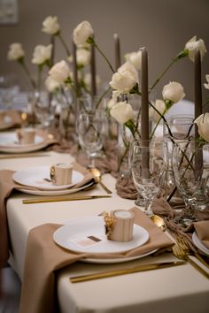 the table is set with white roses and candles