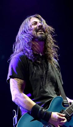 a man with long hair playing an electric guitar