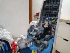 two action figures are shown in front of a fake batman figure and another figurine