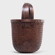 a brown woven basket sitting on top of a white table next to a wooden handle