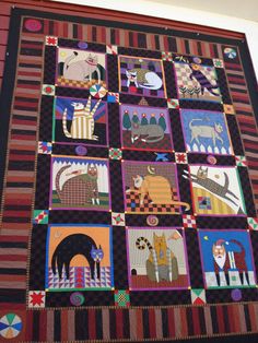 a colorful quilt is hanging on the wall in front of a building with an animal theme