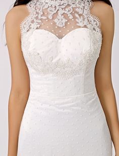 a woman wearing a white wedding dress with sheer neckline and beaded details on the bust